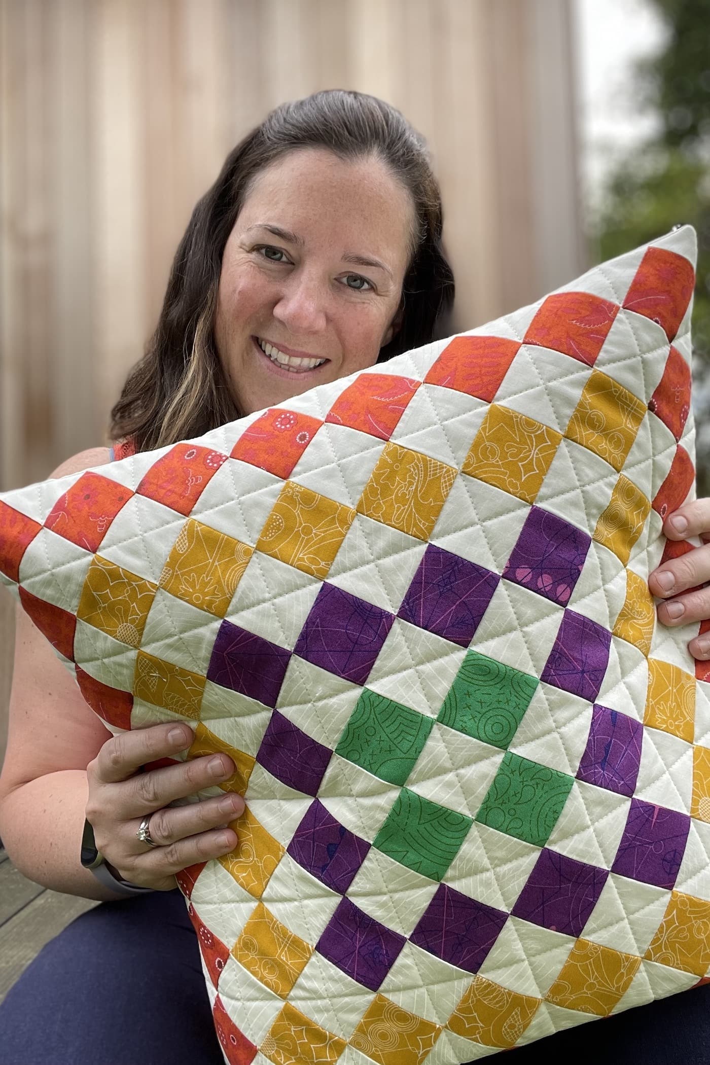 woman holding colorful patchwork pillow