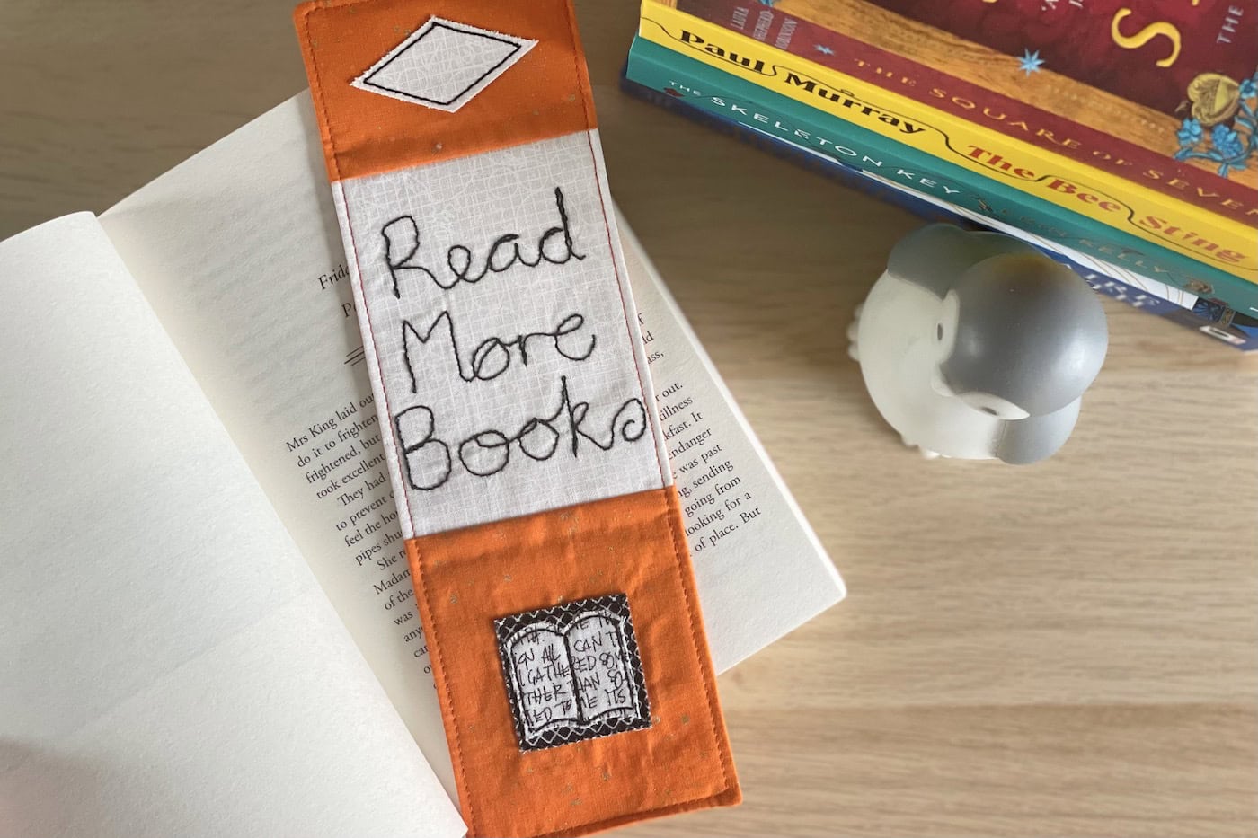 orange bookmark on book on wood table with other books