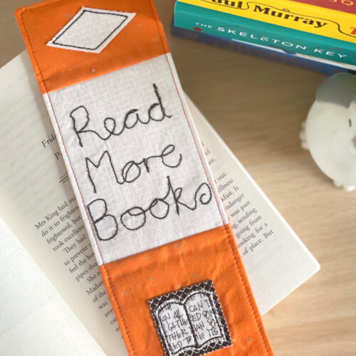 orange bookmark on book on wood table with other books