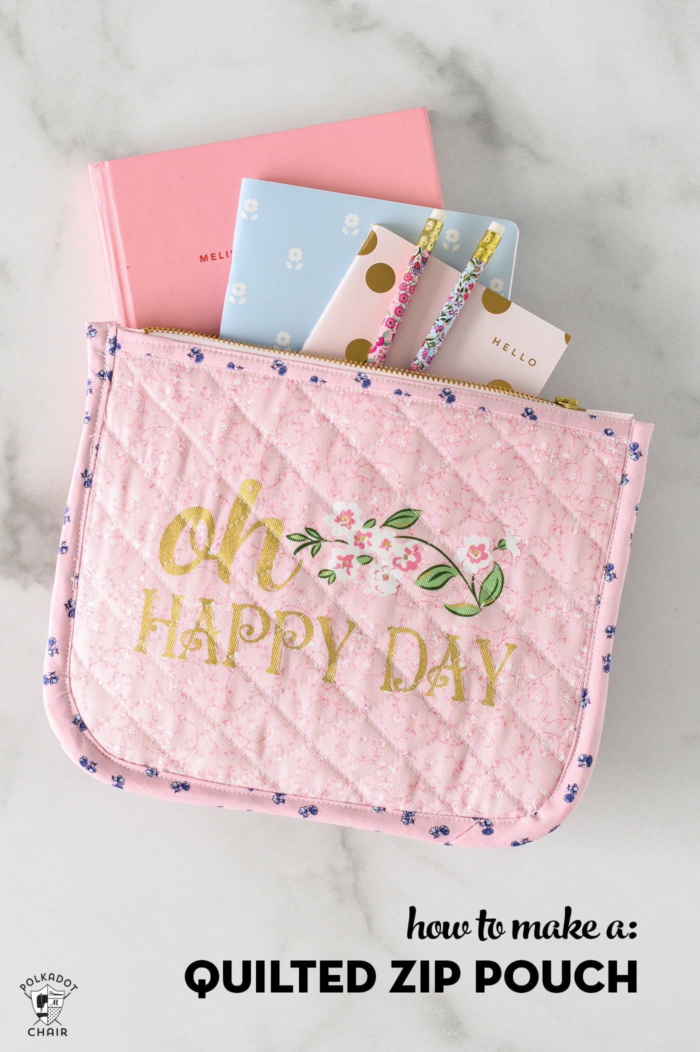 pink quilted zip pouch on white marble table with notebook and pencils