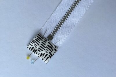 gray zippered bookmark construction process photo - fabric on white table with sewing notions