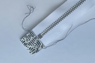 gray zippered bookmark construction process photo - fabric on white table with sewing notions