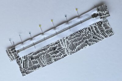 gray zippered bookmark construction process photo - fabric on white table with sewing notions