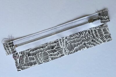 gray zippered bookmark construction process photo - fabric on white table with sewing notions