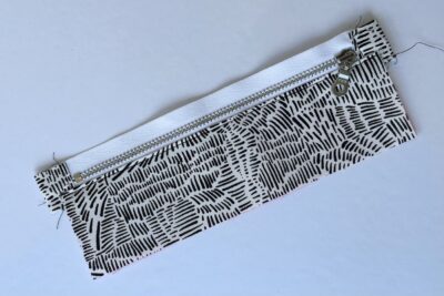 gray zippered bookmark construction process photo - fabric on white table with sewing notions