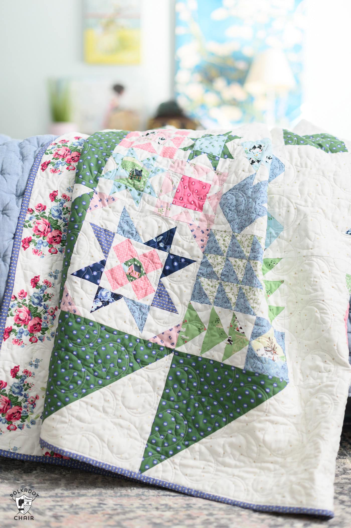 blue, green and pink quilt on bed in bright room