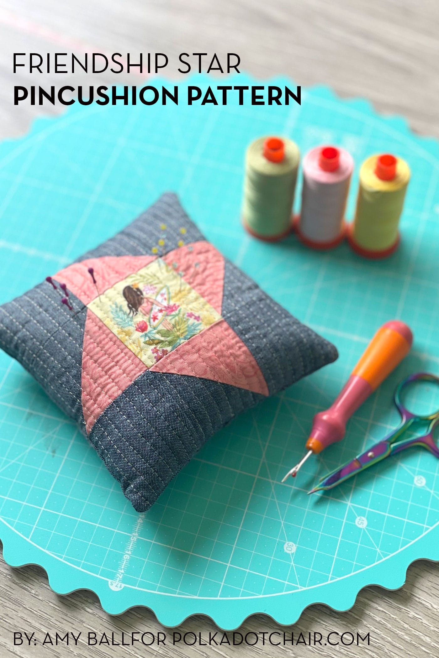 gray and coral pincushion on aqua table with pins and sewing notions